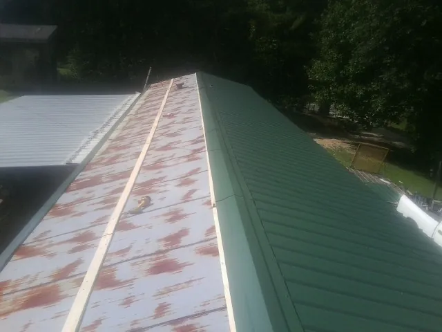 Old rusted panels beside newly installed green metal roofing — Wind Damage Roof Repair by Roofing Brothers in Pomona
