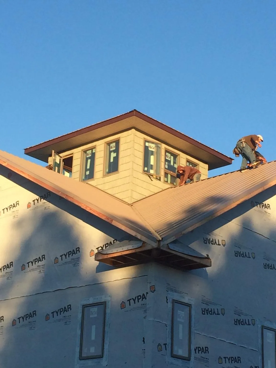 Roofers working around a rooftop cupola on a new metal roof at sunset — Roof Waterproofing in Pomona by Roofing Brothers